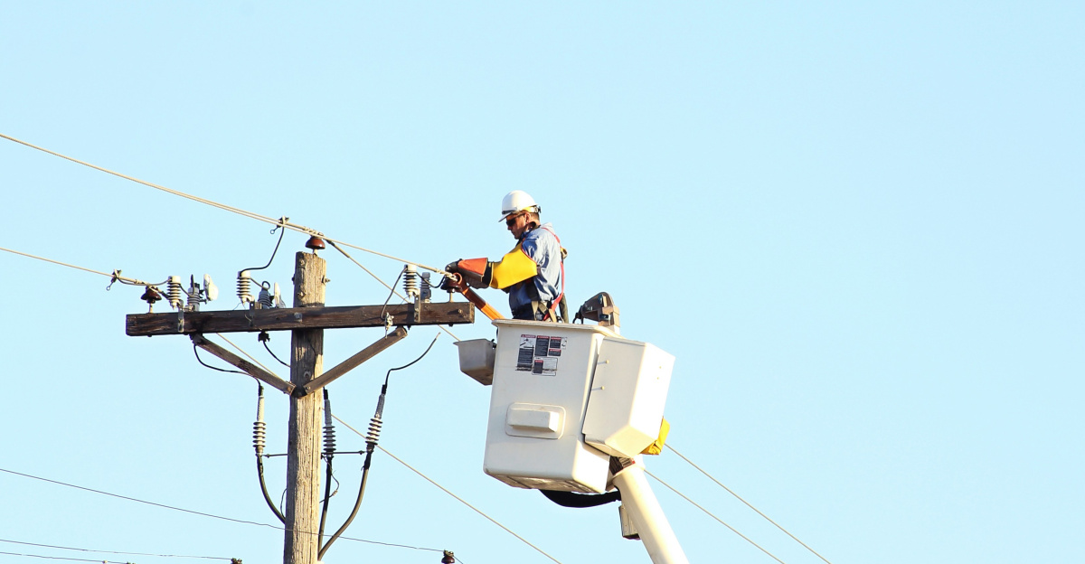 man standing on bucket beside gray current post at daytime
