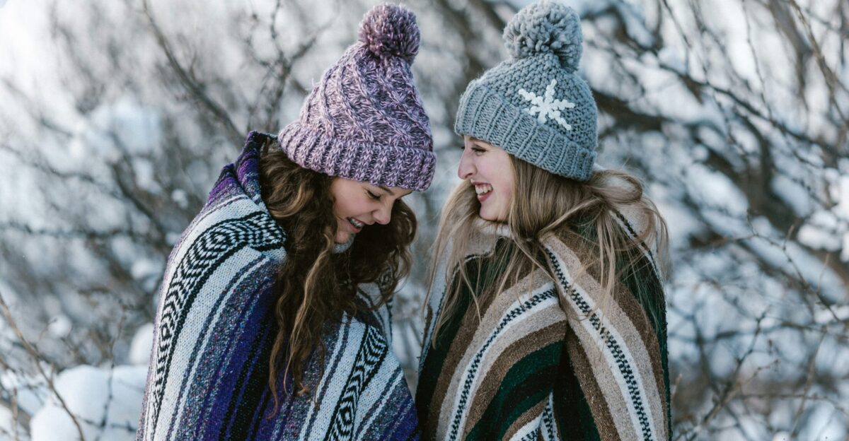 two women in multicolored striped blanket standing near tree