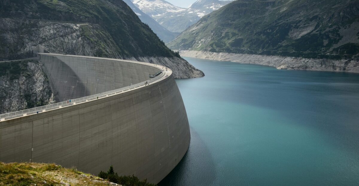 photo of concrete dam in lake near mountains during daytime