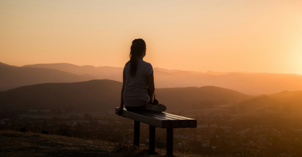 woman sitting on bench over viewing mountain