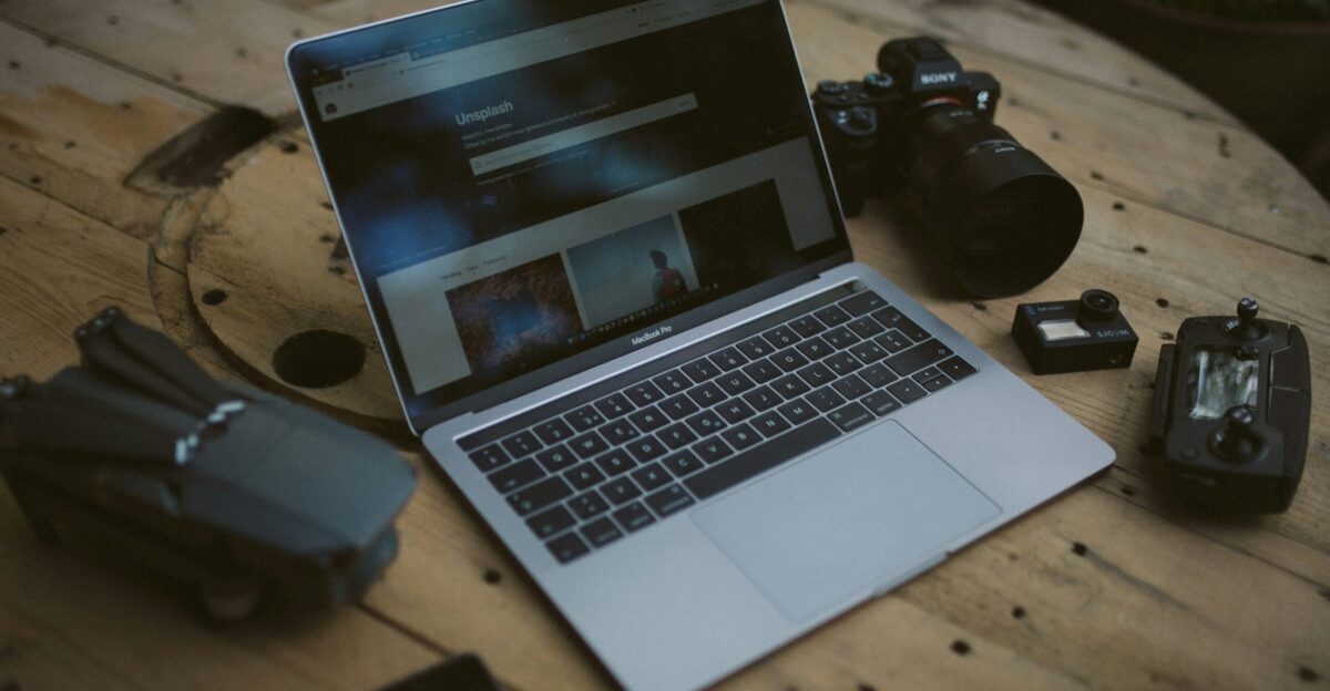 silver MacBook Air and SLR camera on table