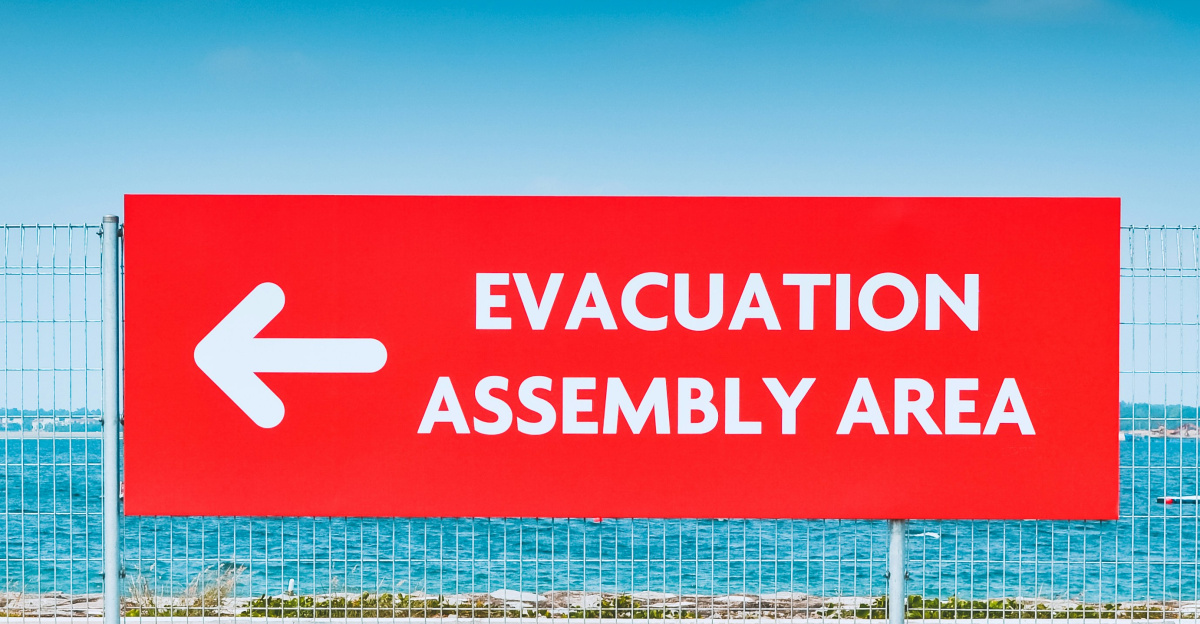 man sitting beside the road while holding an umbrella