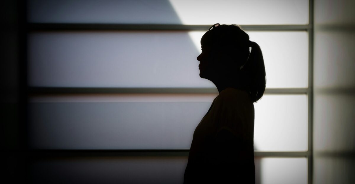 silhouette photo of woman standing near white framed glass window