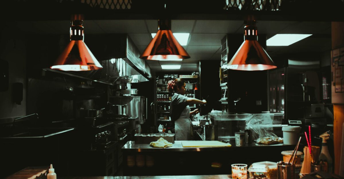 woman standing near three red pendant lamps