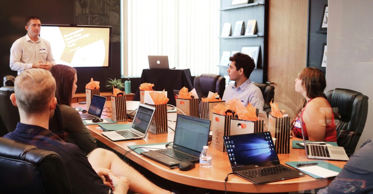 man standing in front of people sitting beside table with laptop computers