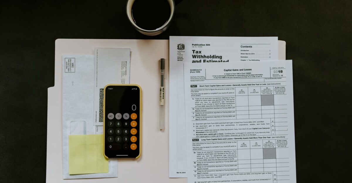 black Android smartphone near ballpoint pen tax withholding certificate on top of white folder