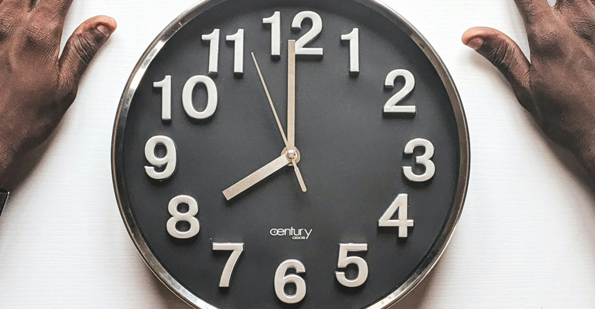 round black and white analog wall clock in front of man