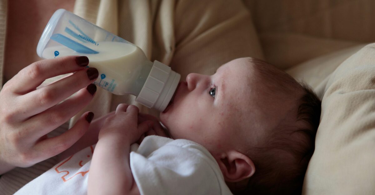 a woman feeding a baby with a bottle of milk