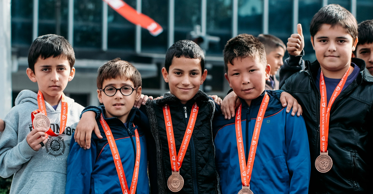 group of children wearing medal standing near wall