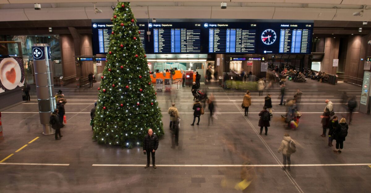 group of people inside building with Christmas tree