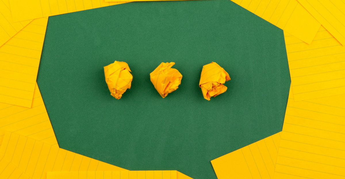 three crumpled yellow papers on green surface surrounded by yellow lined papers
