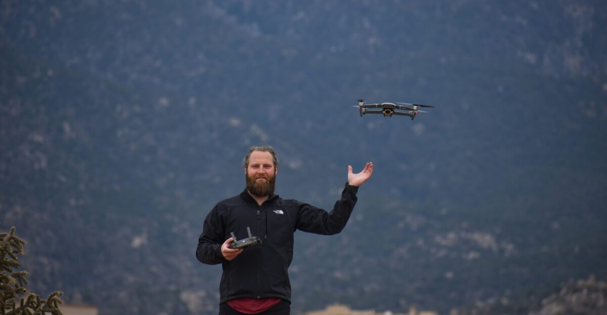 man in black jacket holding black and gray drone