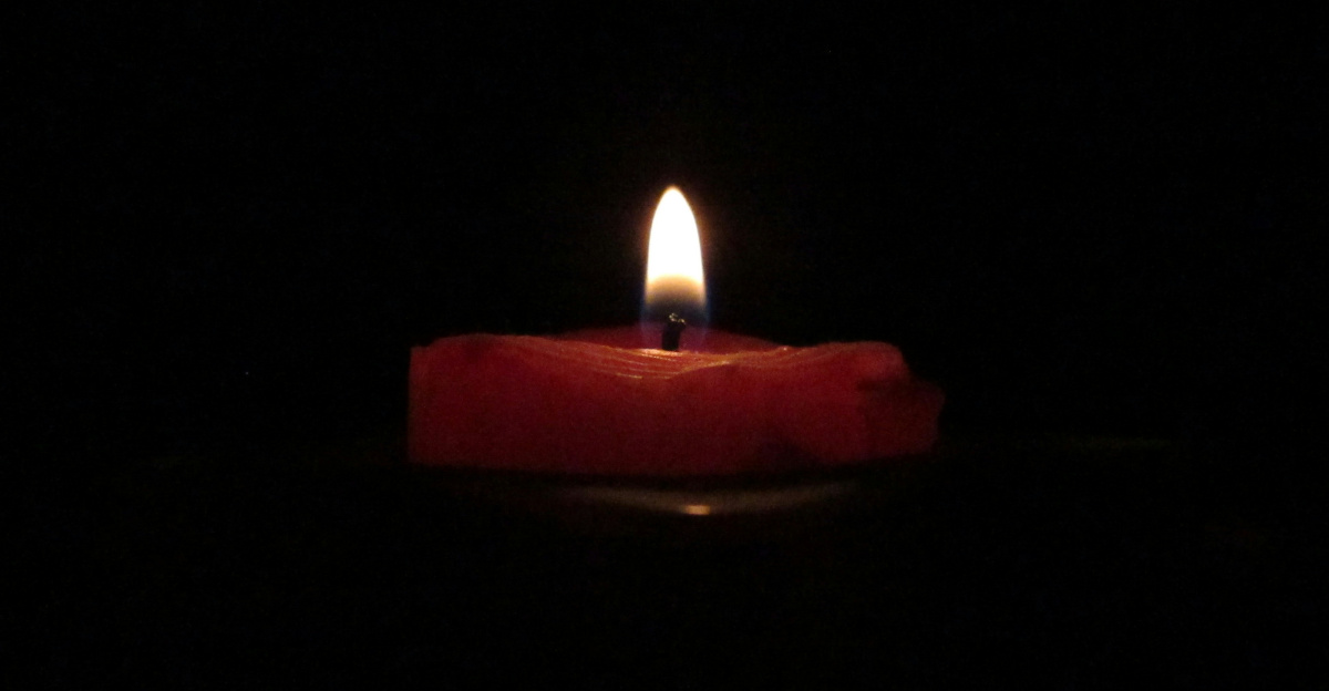red lighted candle on dark room