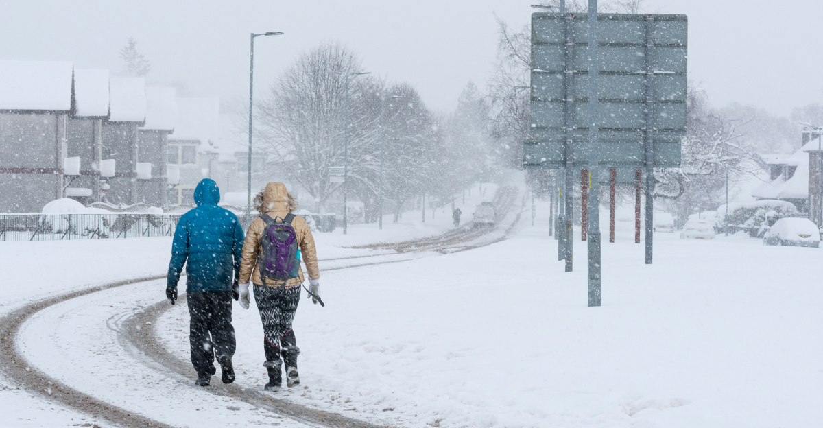 2 person walking on snow covered road during daytime