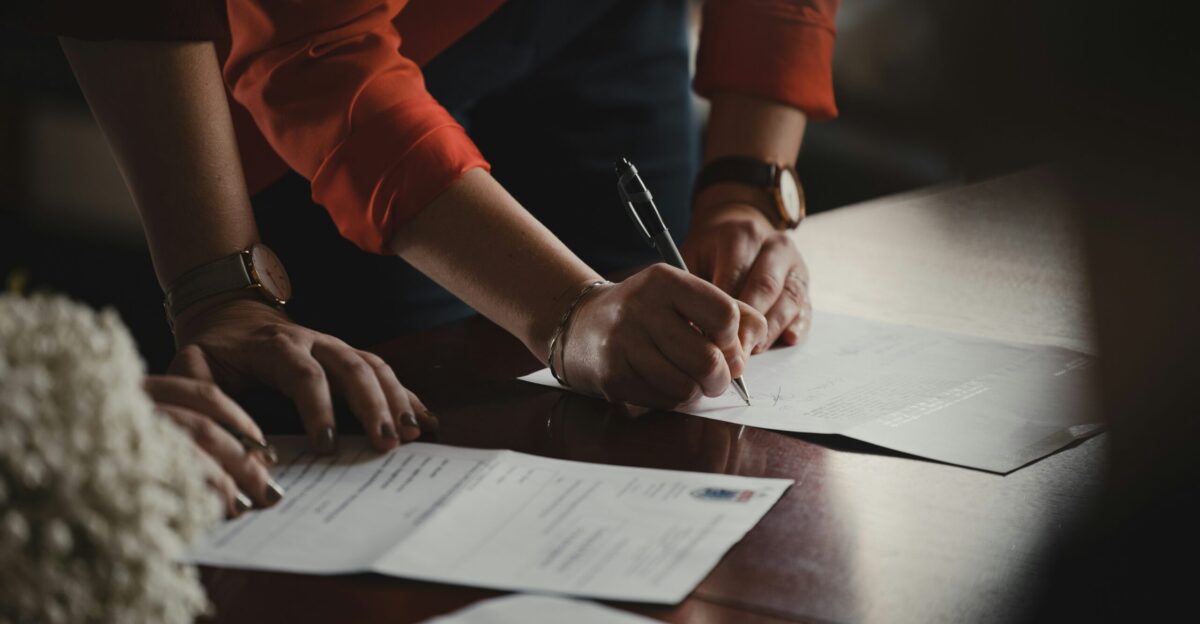 person in orange long sleeve shirt writing on white paper