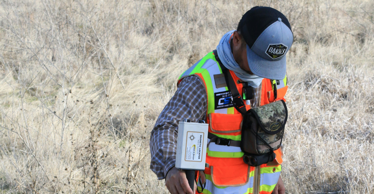 man in orange and black backpack and blue denim jeans standing on brown grass field during