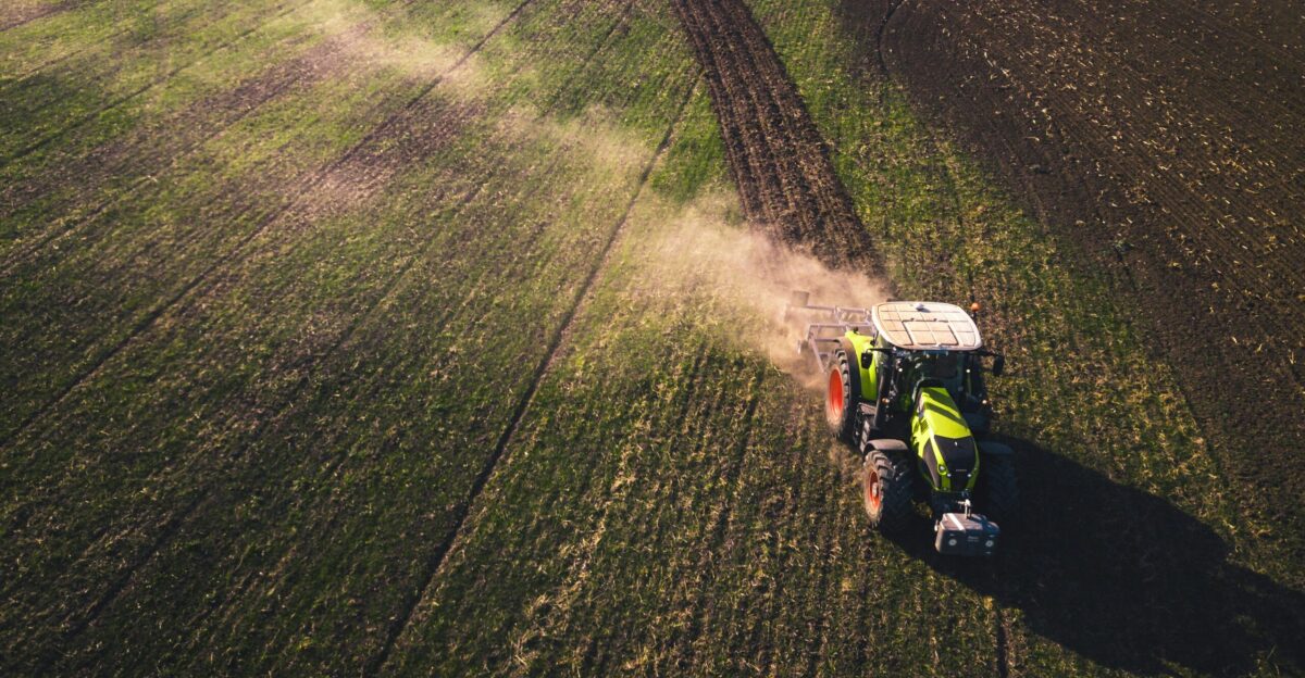 green and white tractor on green grass field during daytime