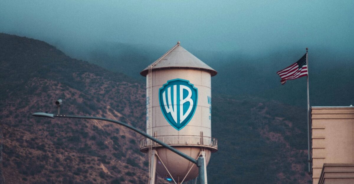 a water tower with a sign on it in front of a mountain