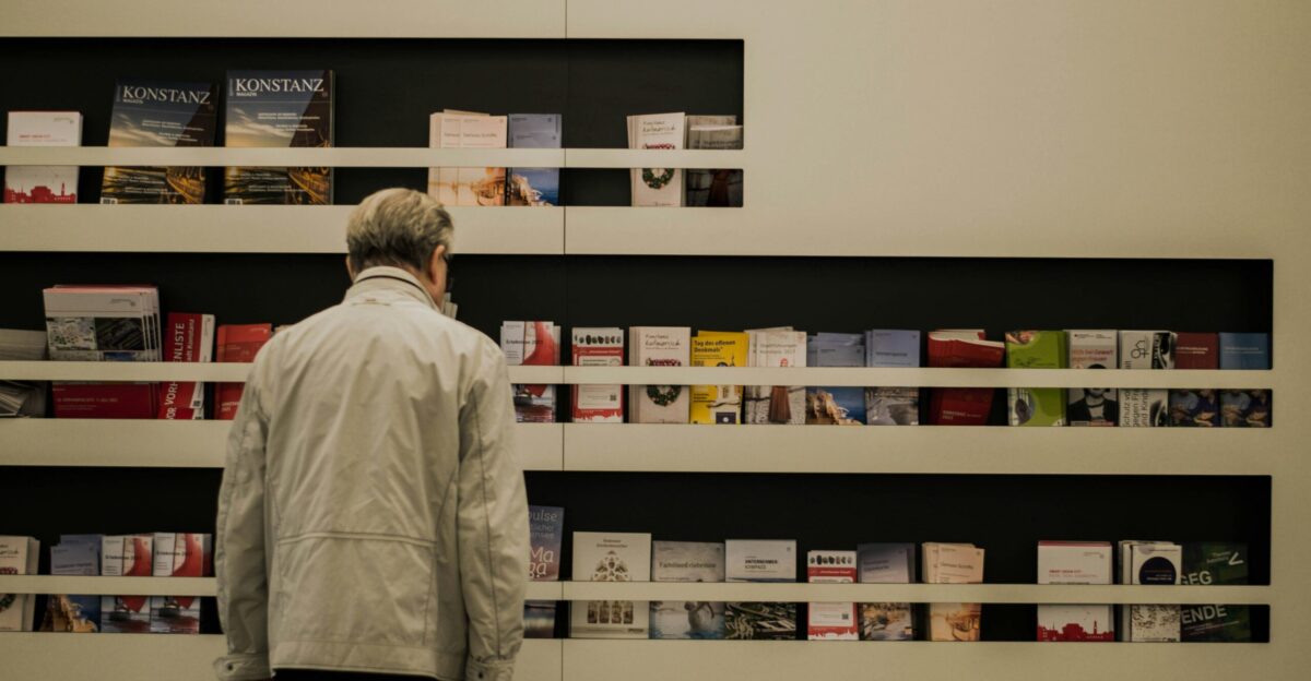 man in white dress shirt standing near white wooden shelf