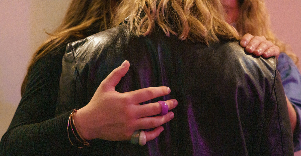 a woman in a black leather jacket holding onto a purple jacket