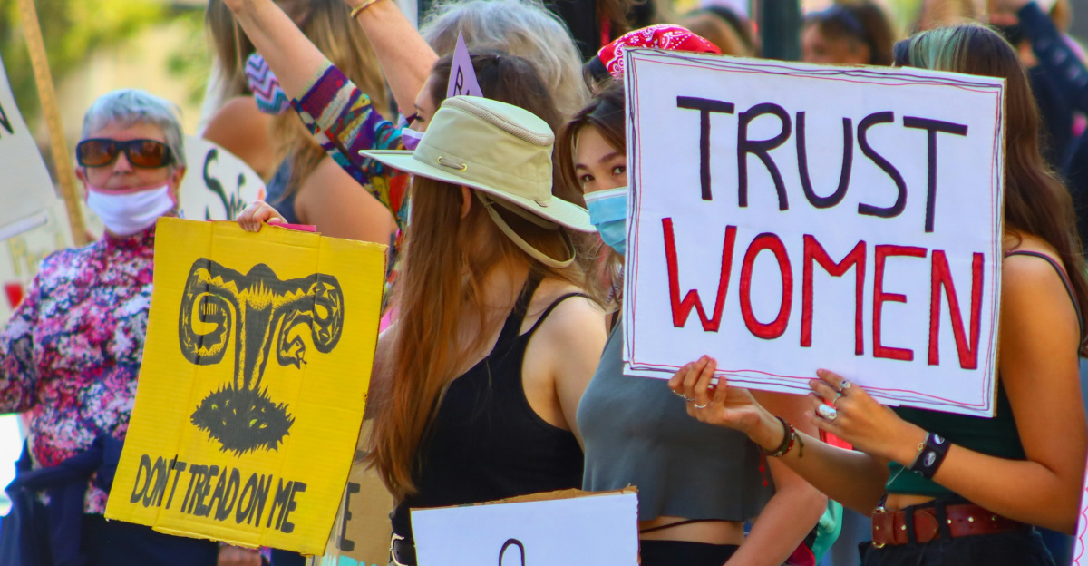 a group of women holding signs and wearing masks