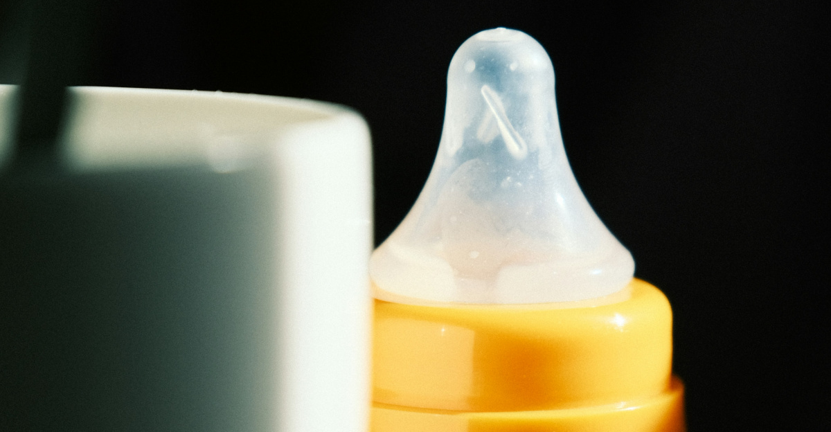 a baby bottle sitting next to a cup