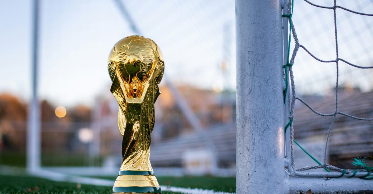 a golden soccer trophy sitting on top of a soccer field