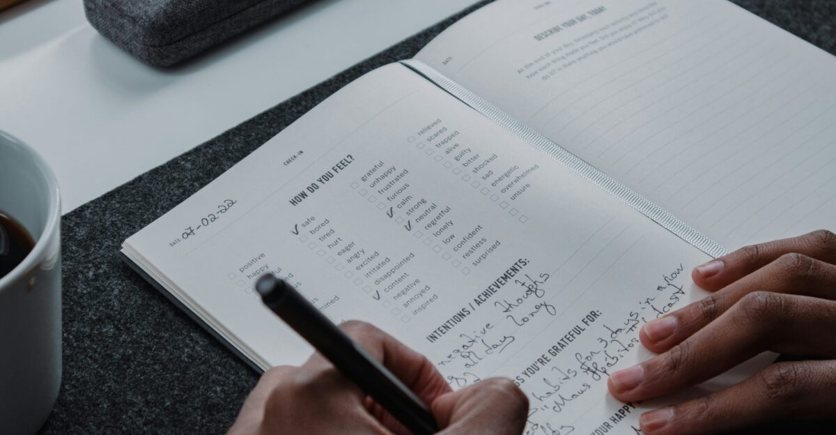 a person writing on a notebook with a pen