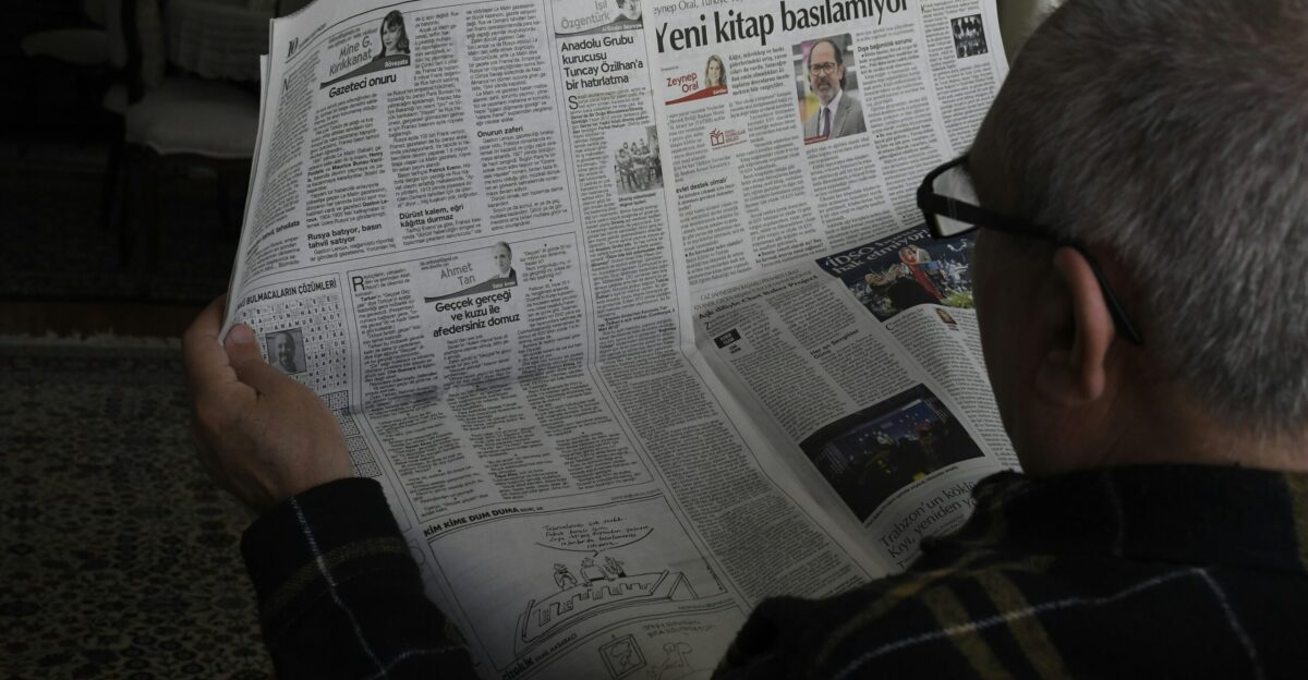 a man reading a newspaper while wearing glasses