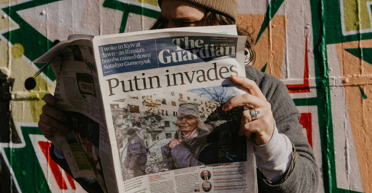 a man reading a newspaper in front of a graffiti covered wall