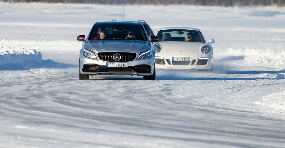a couple of cars driving down a snow covered road