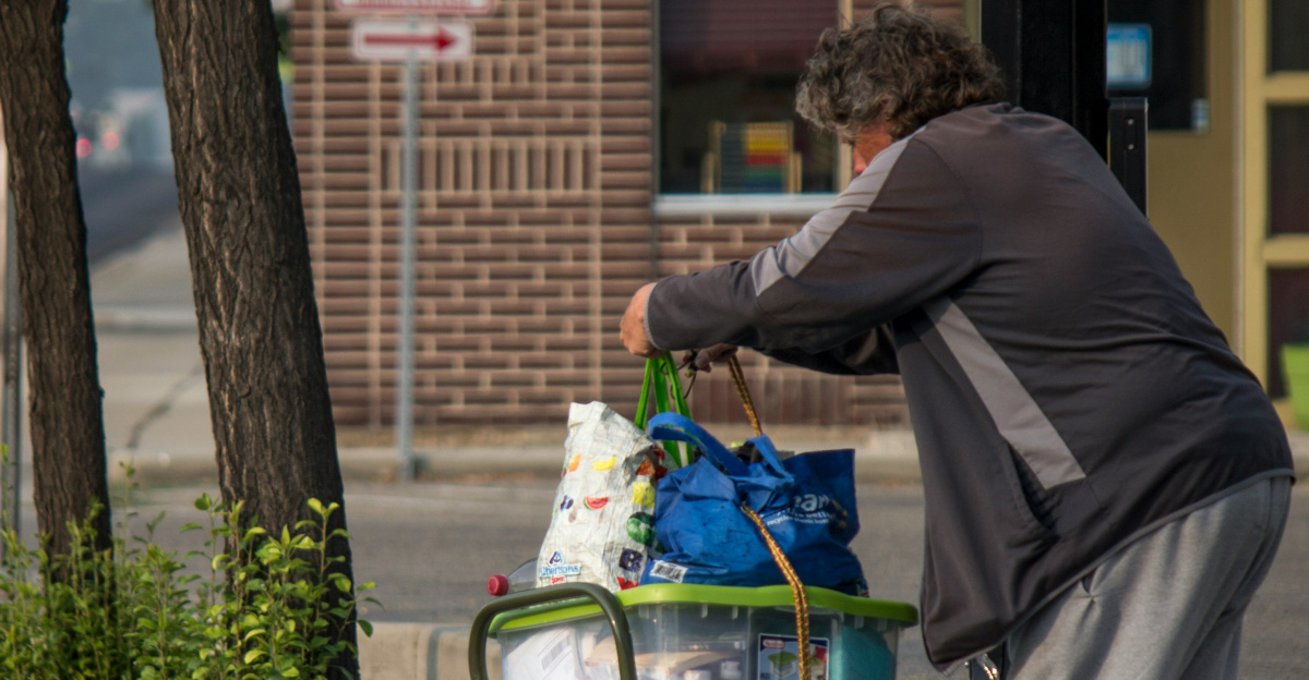 a man pushing a cart full of items on a sidewalk