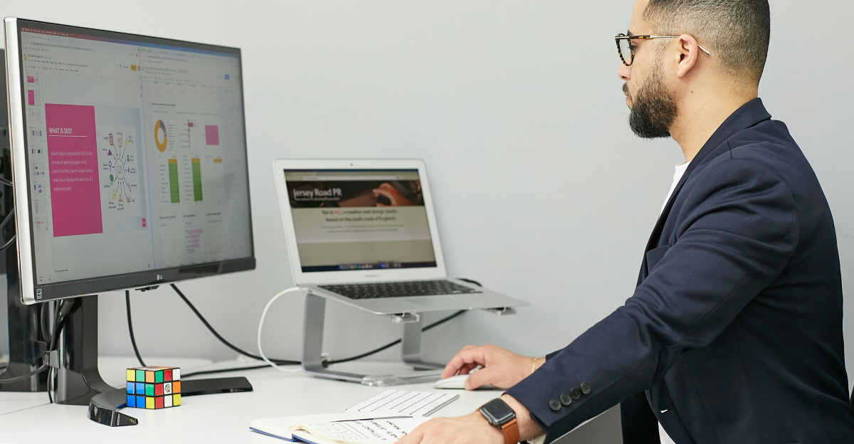 a man sitting at a desk with a laptop and a computer