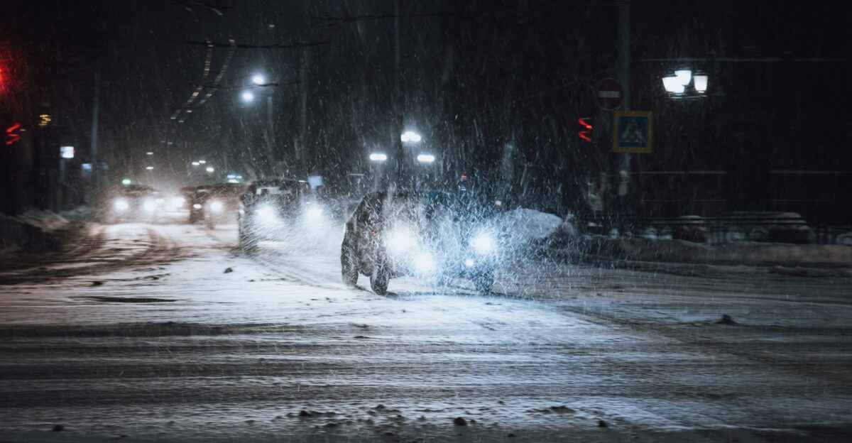 a person walking across a snow covered street at night