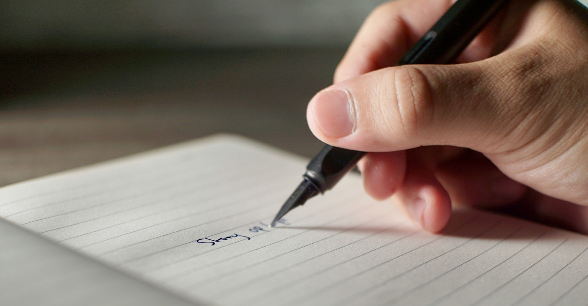 a person writing on a piece of paper with a pen
