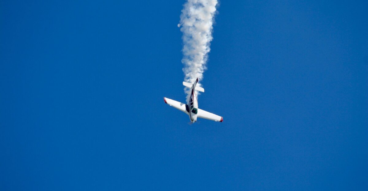 a plane with smoke coming out of it flying in the sky