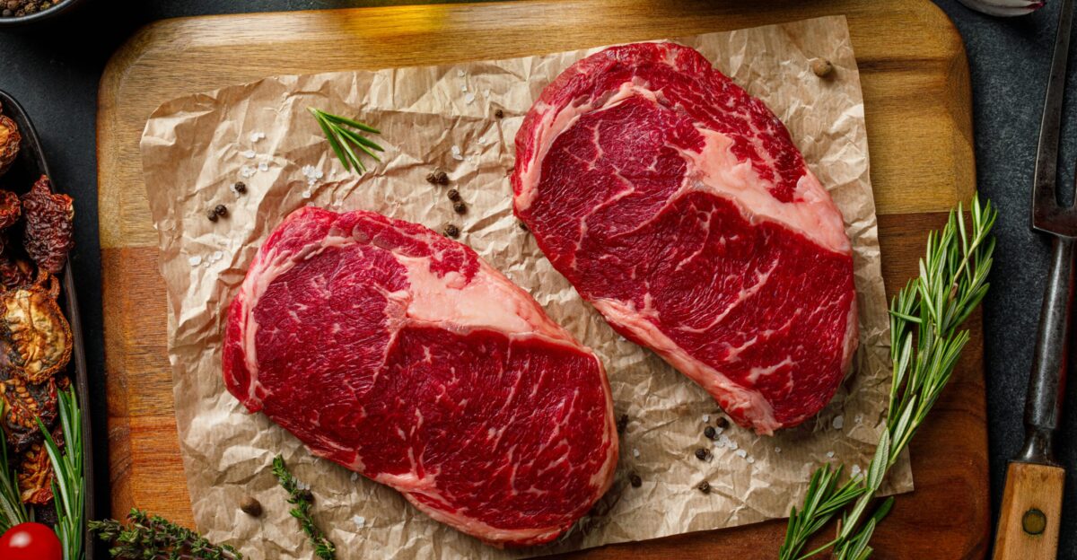 two steaks on a cutting board with herbs and spices