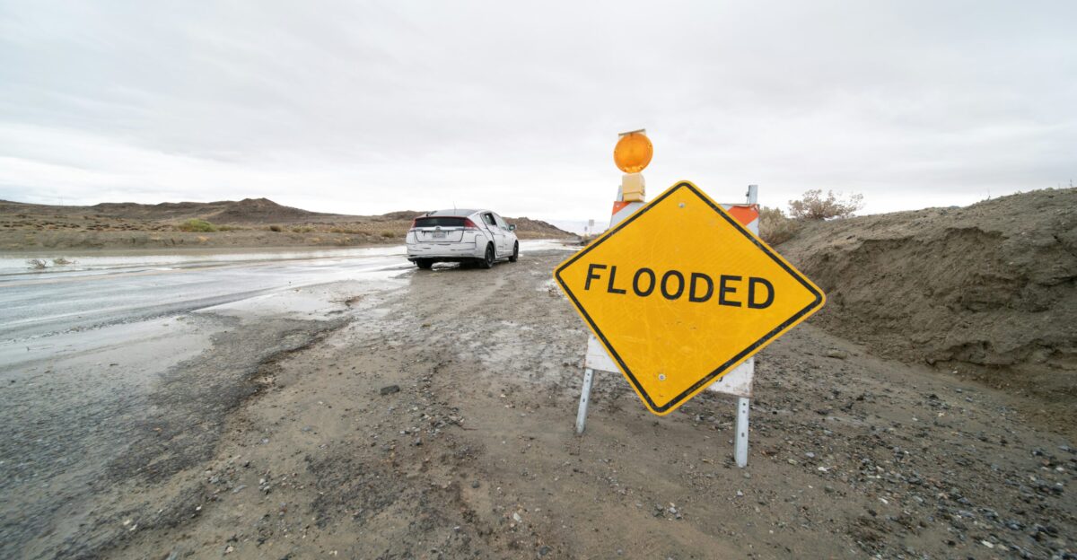 a yellow flood sign sitting on the side of a road