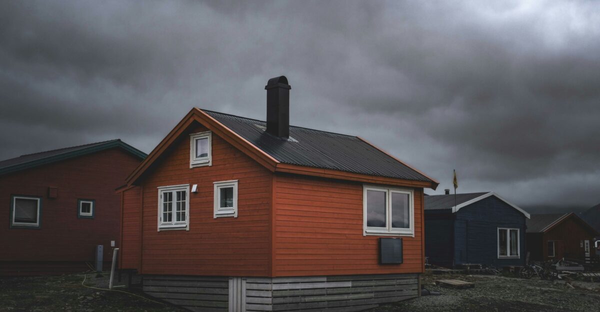 a red house sitting on top of a dirt field
