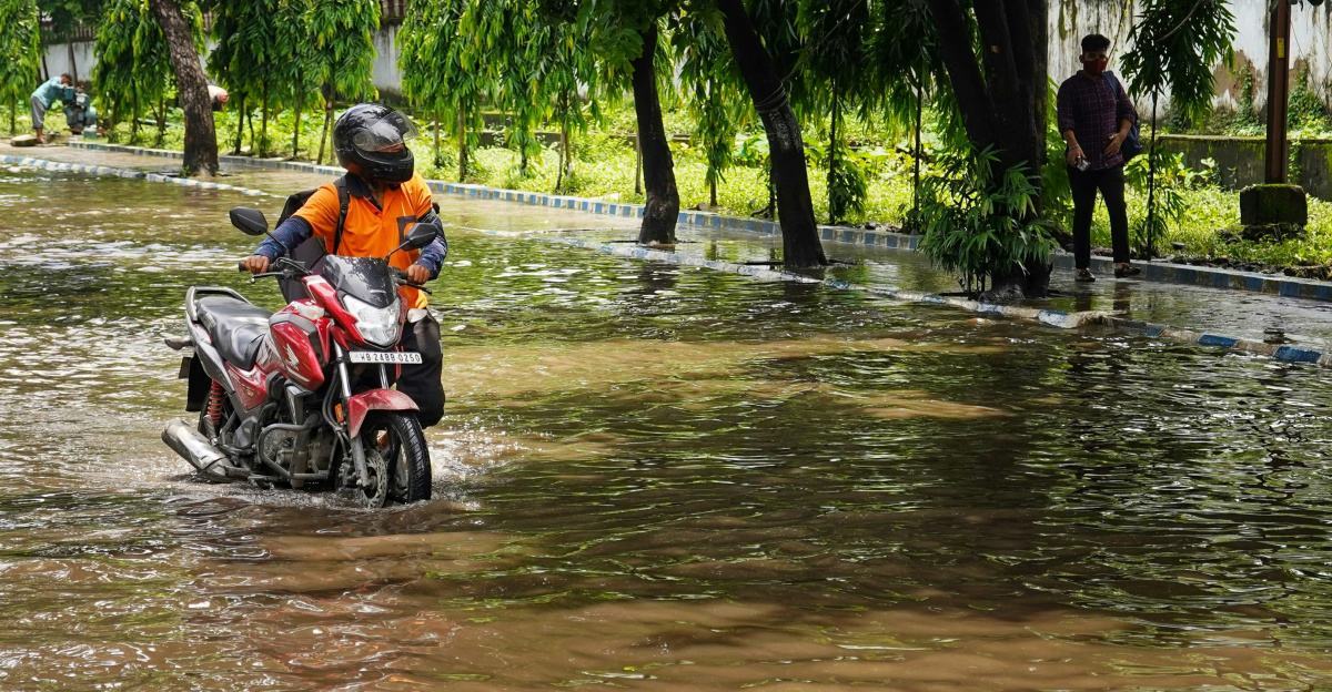 a man riding a motorcycle through a flooded street
