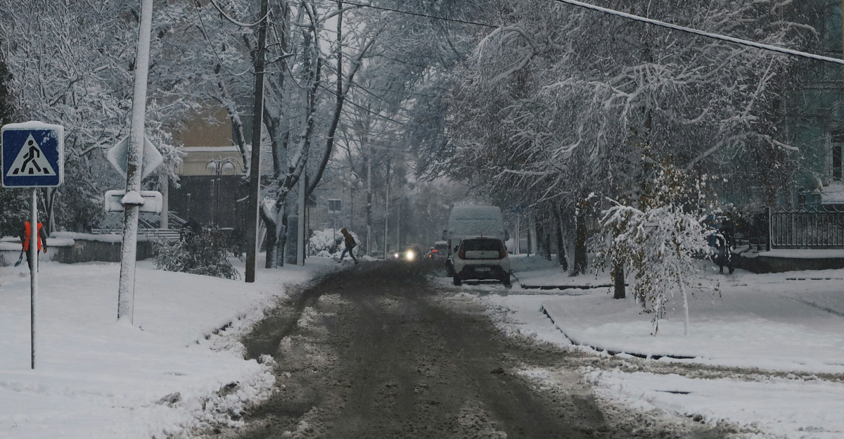 a snowy street with a car driving down it