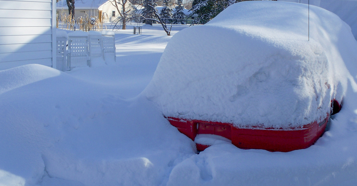 a car covered in snow in front of a house