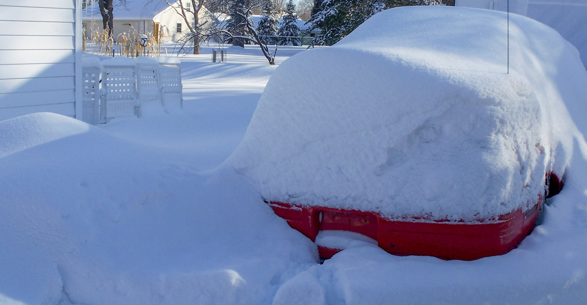a car covered in snow in front of a house
