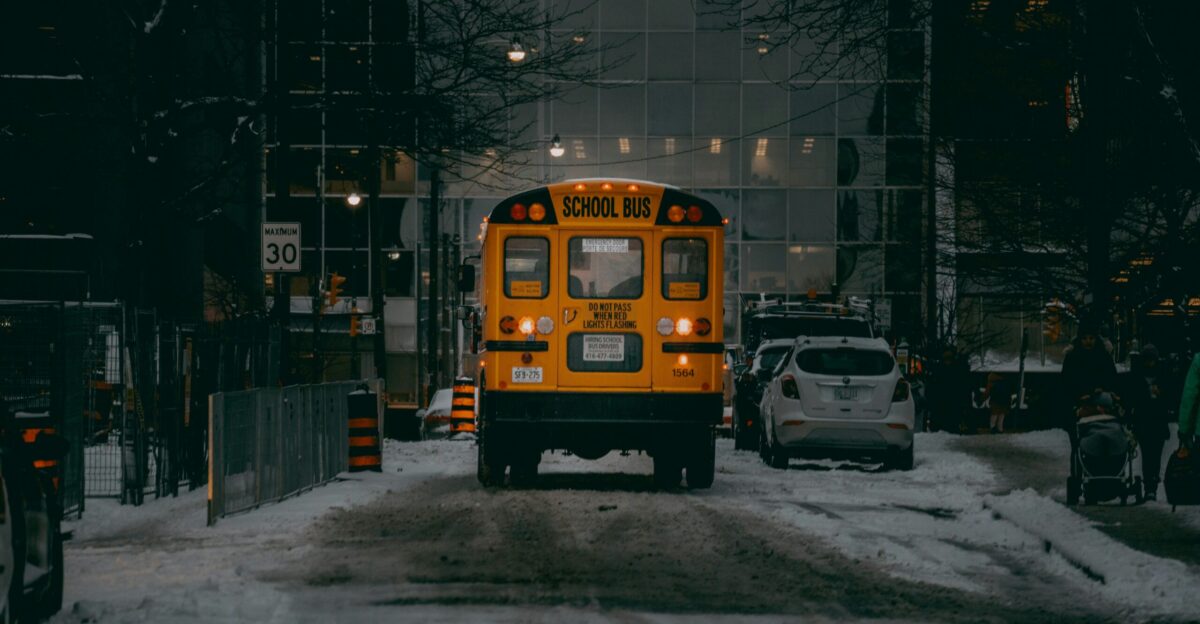 a yellow school bus driving down a snow covered street