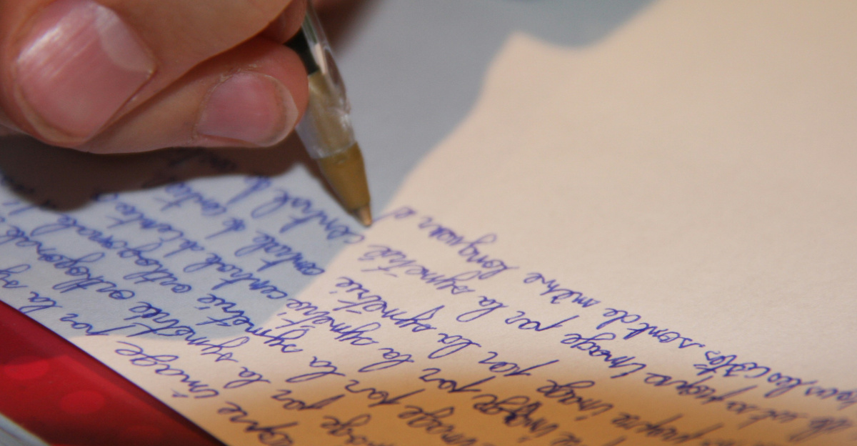 a person writing on a piece of paper with a pen