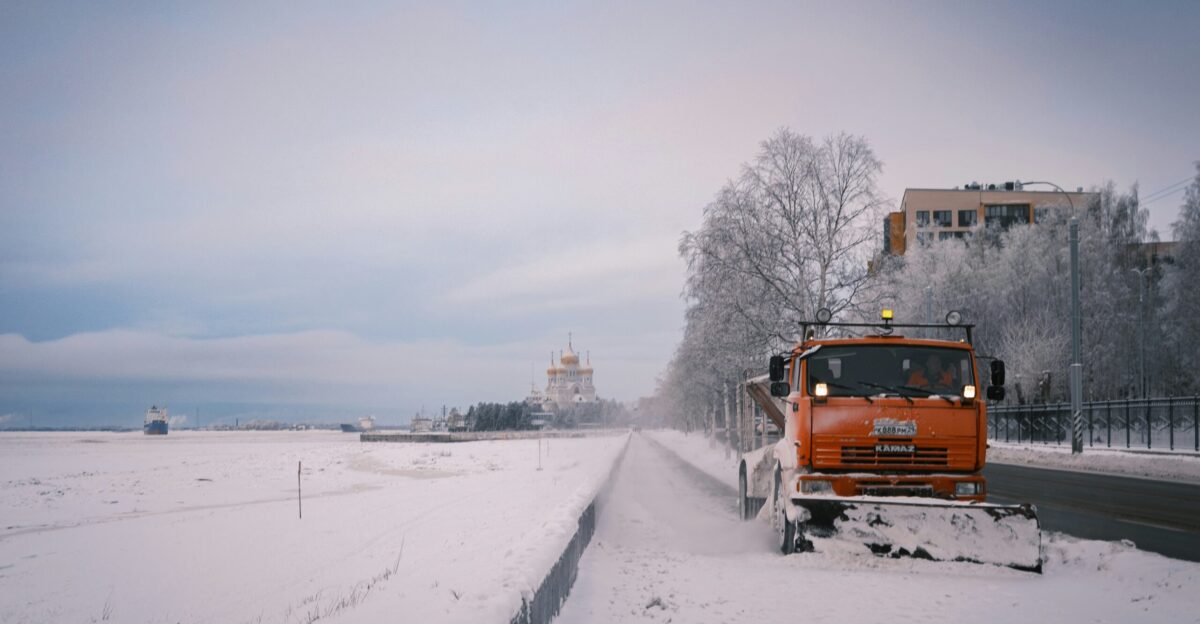 a snow plow is driving down a snowy road