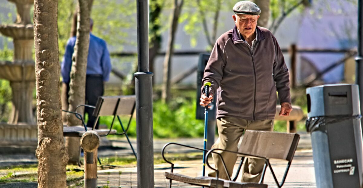 a man walking down a sidewalk next to a park bench