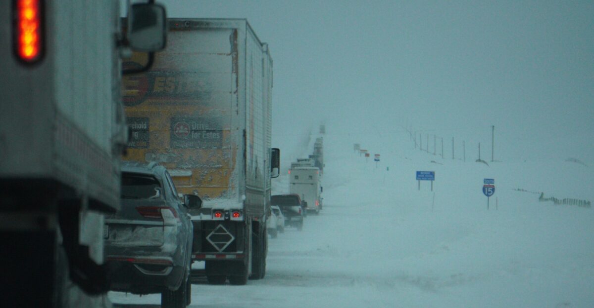 a couple of trucks driving down a snow covered road