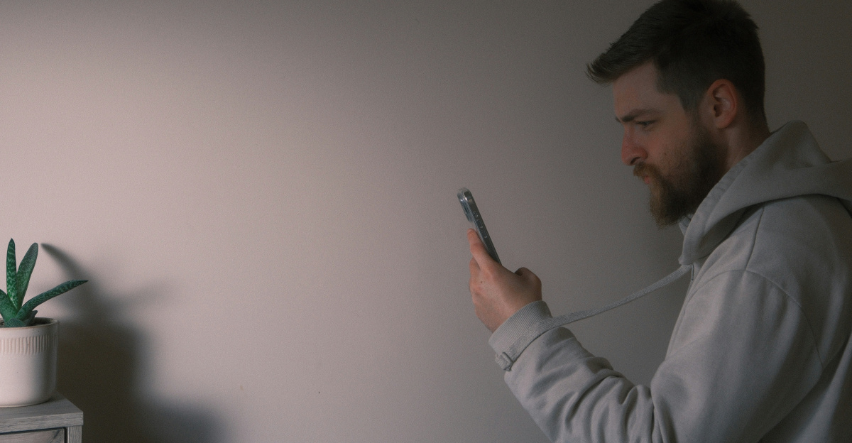 a man holding a cell phone next to a plant