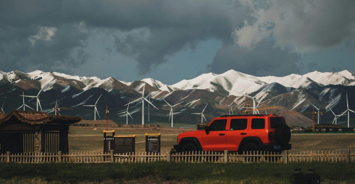 a red truck driving down a road next to a wind farm